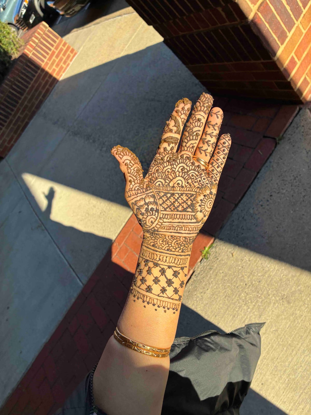 Full palm henna with lattice and floral borders, gold bangles on the wrist