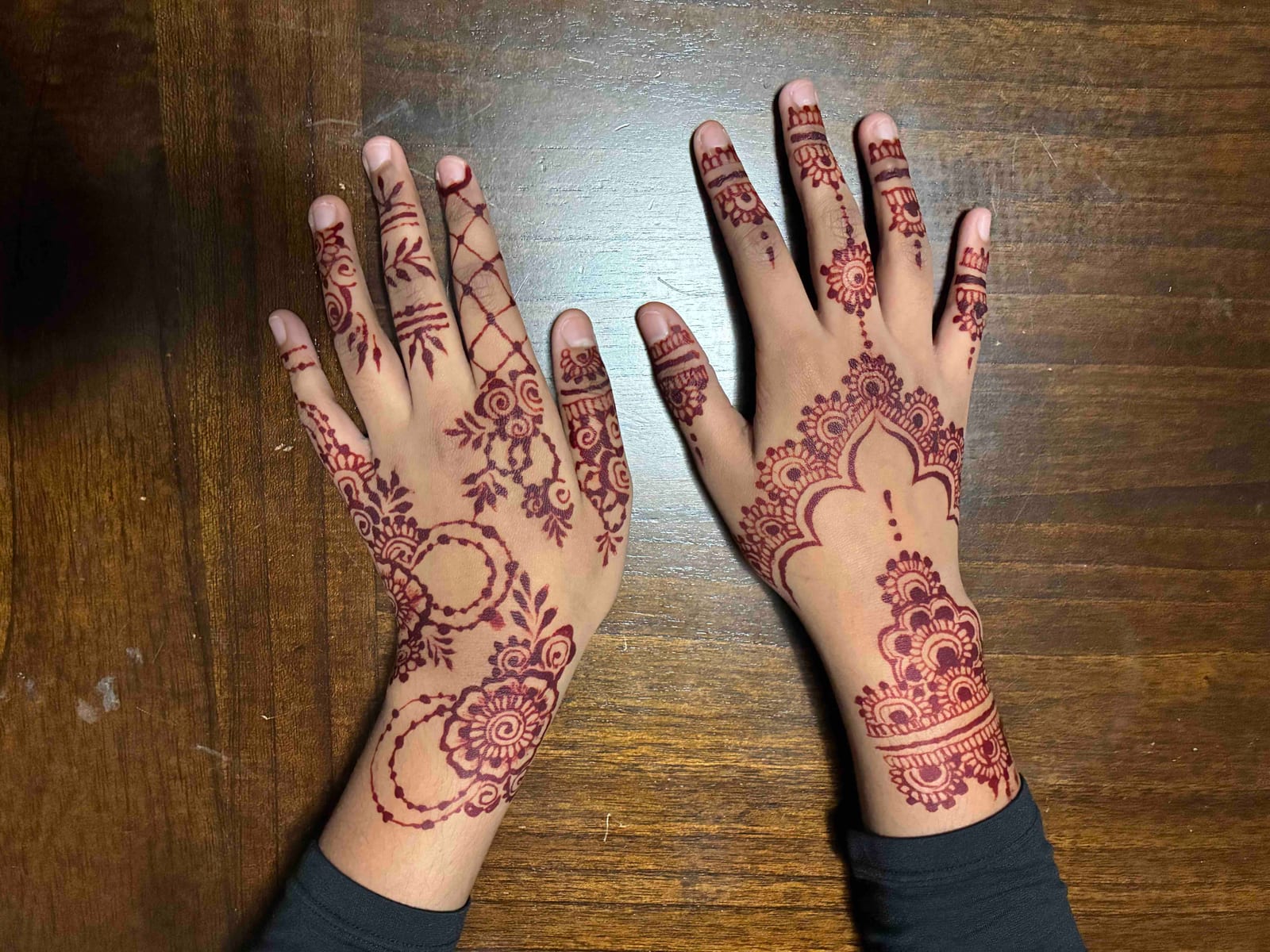 Two hands side by side, back-of-hand henna in coordinated motifs